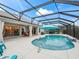 Beautiful screened-in pool area with a waterfall feature and an umbrella offering shade and an open view into the kitchen at 4406 Creighton Loop, The Villages, FL 32163