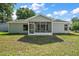 Back of house with a screened-in porch, overlooking the backyard, and mature landscaping at 4553 Belle Grv, Leesburg, FL 34748