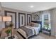 Well-decorated bedroom with a stylish accent wall, comfortable bed, and a view of the outdoors at 5035 Abigail Dr, Lake Wales, FL 33859