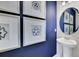 A modern powder room showcases a pedestal sink, framed art prints, and a contemporary round mirror creating an elegant space at 5039 Abigail Dr, Lake Wales, FL 33859