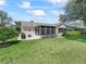 Backyard featuring a screened-in porch, lush green lawn, and mature landscaping at 511 Chula Vista Ave, The Villages, FL 32159