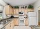 A kitchen with light wood cabinets, white appliances, and granite countertops at 511 Chula Vista Ave, The Villages, FL 32159