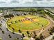 A high-angle shot captures the community's four baseball and softball fields, framed by lush greenery and a parking lot at 5325 Zisa Ct, The Villages, FL 32163