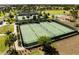 An aerial view of meticulously maintained tennis and pickleball courts in a sunny, lush community at 5325 Zisa Ct, The Villages, FL 32163