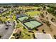 An aerial view of meticulously maintained tennis courts in a sunny, lush community at 5325 Zisa Ct, The Villages, FL 32163
