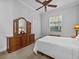 Bright bedroom with neutral walls and carpet features a large window, white comforter and a wooden dresser with mirror at 5530 Oxford Moor Blvd, Windermere, FL 34786
