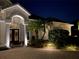 Stunning home exterior showcasing an arched entrance, lush landscaping, and inviting outdoor lighting at night at 5530 Oxford Moor Blvd, Windermere, FL 34786