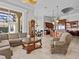 A living room with large windows, a grandfather clock, a glass coffee table, and a view to the kitchen at 5530 Oxford Moor Blvd, Windermere, FL 34786