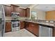 Modern kitchen with stainless steel appliances, granite countertops, and dark wood cabinets at 5941 Sage Leaf Pl, Leesburg, FL 34748