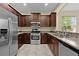Modern kitchen with stainless steel appliances, granite countertops, and dark wood cabinets at 5941 Sage Leaf Pl, Leesburg, FL 34748