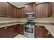 Well-equipped kitchen featuring stainless steel appliances, granite countertops, and dark wood cabinets at 5941 Sage Leaf Pl, Leesburg, FL 34748