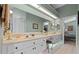Bright bathroom featuring dual sinks, white cabinetry, and a large mirror with vanity lighting at 6608 Borg, Leesburg, FL 34748