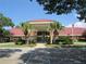 Inviting exterior of a community clubhouse, featuring palm trees and a well-manicured lawn at 6608 Borg, Leesburg, FL 34748