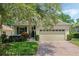 Charming single-story home featuring a brick driveway, attached garage, and mature landscaping with a tree with Spanish moss at 791 Wolf Creek St, Clermont, FL 34711