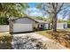 Single Gathering home showcasing mature trees, a two-car garage, and cozy front porch at 8158 Bucksaw Dr, Orlando, FL 32817