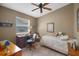 A cozy bedroom is furnished with a ceiling fan, a desk, a bed, and carpeted floors at 830 Grand Vista Trl, Leesburg, FL 34748