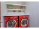 Bright laundry room with red washer and dryer and custom shelving for storage and decor at 910 Locust St, New Smyrna Beach, FL 32169