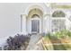 Close-up of home's arched doorway with sidelights and a brick path lined with greenery at 981 Piedmont Oaks Dr, Apopka, FL 32703