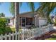 Exterior of a charming home showcasing a screened in porch, white picket fence, and well manicured landscaping at 992 Pinewood Pl, The Villages, FL 32162