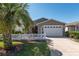 Charming single story home featuring a white picket fence, well-manicured lawn, and a driveway leading to the garage at 992 Pinewood Pl, The Villages, FL 32162
