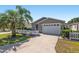 Charming single story home featuring a white picket fence, well-manicured lawn, and a driveway leading to the garage at 992 Pinewood Pl, The Villages, FL 32162