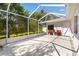 Enclosed patio featuring neutral tiled floor, two red chairs, and surrounding greenery with a white back door at 1037 Willow Dr, Leesburg, FL 34748