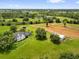 Areal view of a sprawling property with a well-manicured lawn, home, garage, barn, and verdant trees at 10901 Island Grove Rd, Clermont, FL 34711