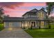 Charming two-story house featuring a covered porch, wood accents, manicured shrubs and a brick paved driveway at 10901 Island Grove Rd, Clermont, FL 34711