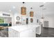 Kitchen island with white marble countertops, gray laminate flooring, and stylish pendant lighting at 10901 Island Grove Rd, Clermont, FL 34711