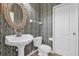 Charming powder room featuring patterned wallpaper and a pedestal sink at 10901 Island Grove Rd, Clermont, FL 34711