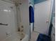 Standard white tub/shower combo with safety bar, white tile walls, and updated showerhead with blue accent wall at 11250 Sw 78Th Ct, Ocala, FL 34476