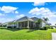 Backyard view of the home showing the lanai, manicured lawn, and lush landscaping at 1172 Fiesta Key Cir, Lady Lake, FL 32159