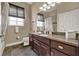 Bathroom with granite-topped vanity, dark wood cabinets, large mirror, and natural light from window at 1172 Fiesta Key Cir, Lady Lake, FL 32159
