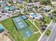 Aerial view showcasing a basketball court, tennis courts and community pool amid lush landscaping and colorful homes at 1172 Fiesta Key Cir, Lady Lake, FL 32159