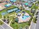 Aerial view of community pool and tennis courts, along with colorful homes under construction nearby at 1172 Fiesta Key Cir, Lady Lake, FL 32159