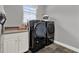 Laundry room features side-by-side, front-loading washer and dryer, white cabinets, and gray walls at 1172 Fiesta Key Cir, Lady Lake, FL 32159