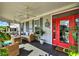 Inviting screened-in porch featuring wicker furniture, ceiling fans, and a vibrant red front door at 1172 Fiesta Key Cir, Lady Lake, FL 32159