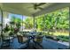 Screened-in porch featuring wicker chairs, a ceiling fan, and a table setting for a picturesque outdoor dining space at 1172 Fiesta Key Cir, Lady Lake, FL 32159