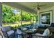 Screened porch with table set for four, wicker chairs, ceiling fan, and view of backyard at 1172 Fiesta Key Cir, Lady Lake, FL 32159