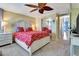 Bright bedroom features a large bed with red patterned bedding, a leaf-shaped ceiling fan, and sliding closet doors at 1401 W Highway 50 # 142, Clermont, FL 34711