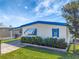 Well-maintained mobile home with blue trim, awning, and landscaped yard on a sunny day at 1401 W Highway 50 # 143, Clermont, FL 34711