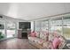 The sun room features a wicker couch, a large TV, light-filled windows, and modern wood-style flooring at 150 Hickory Ln, Eustis, FL 32726