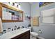 A quaint bathroom features a wood framed mirror, neutral paint, a white vanity, and a tiled shower at 1554 Sarus Ave, Groveland, FL 34736