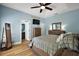 Comfortable primary bedroom featuring soft blue walls, wood-look floors, and en-suite bathroom entrance at 1554 Sarus Ave, Groveland, FL 34736