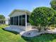 Home exterior featuring a screened-in lanai, manicured lawn and surrounding landscaping at 17374 Se 76Th Flintlock Ter, The Villages, FL 32162