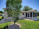 Charming home exterior with lush lawn, attractive tree, rock beds, and enclosed patio area at 17374 Se 76Th Flintlock Ter, The Villages, FL 32162