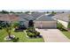 Charming home featuring manicured lawn, ornamental landscaping, and a patterned driveway leading to a two-car garage at 1754 Pennecamp Dr, The Villages, FL 32162