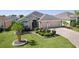 Attractive home with well-kept lawn, shrubbery, palm trees, and a decorative driveway leading to a two-car garage at 1754 Pennecamp Dr, The Villages, FL 32162