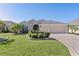 Charming single-story home featuring a manicured lawn, landscaped garden beds, and a welcoming two-car garage at 1754 Pennecamp Dr, The Villages, FL 32162