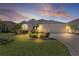 Inviting home exterior at dusk, enhanced by landscape lighting, highlighting the well-maintained lawn and garden at 1754 Pennecamp Dr, The Villages, FL 32162